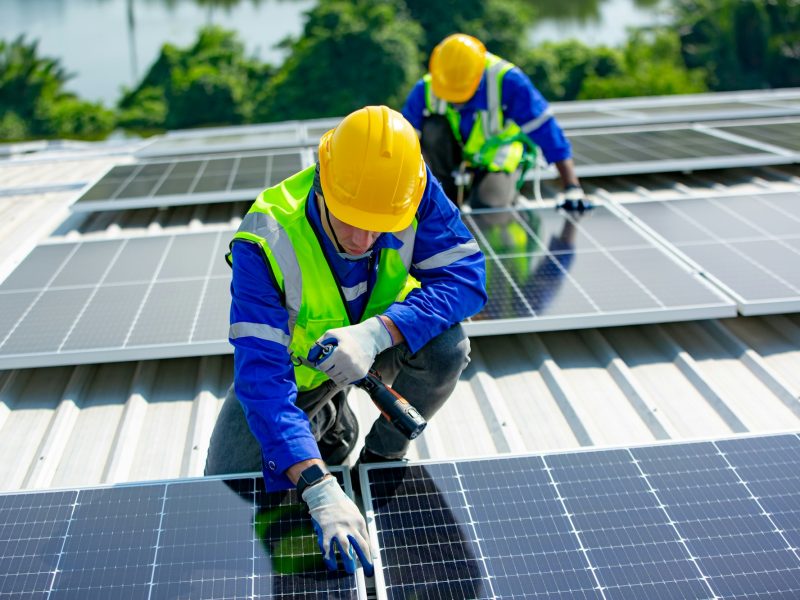 Solar panel installer installing solar panels on roof of warehouse