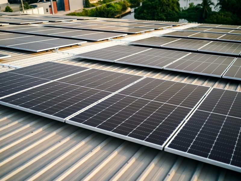 Solar panel installer installing solar panels on roof of warehouse