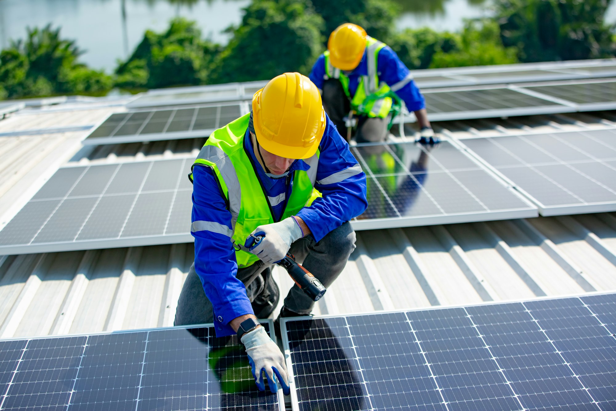 Solar panel installer installing solar panels on roof of warehouse